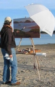 Rosalie Nadeau plein air painting on her Take It Easel, with an umbrella attached to her plein air portable easel